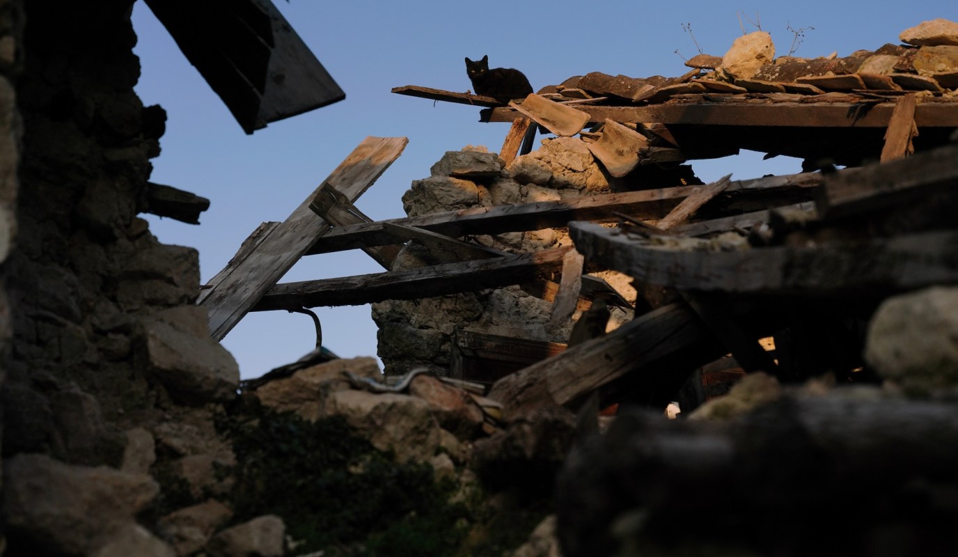 A black cat perched on a collapsed building.