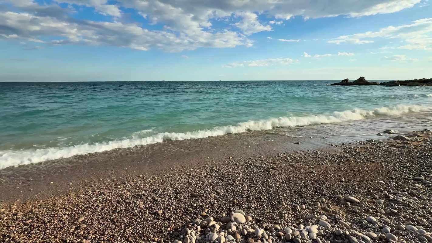 Gentle waves lapping at pebbles at a beach.