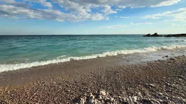 Gentle waves lapping at pebbles at a beach.