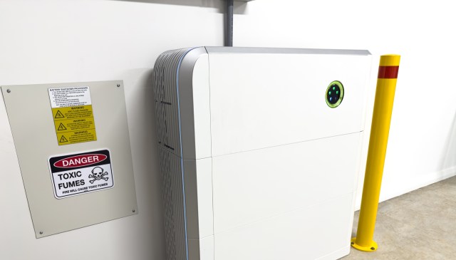A battery unit next to a warning sign about toxic fumes and a yellow safety pole.
