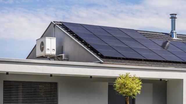 A house with rooftop solar panels and a heat pump.