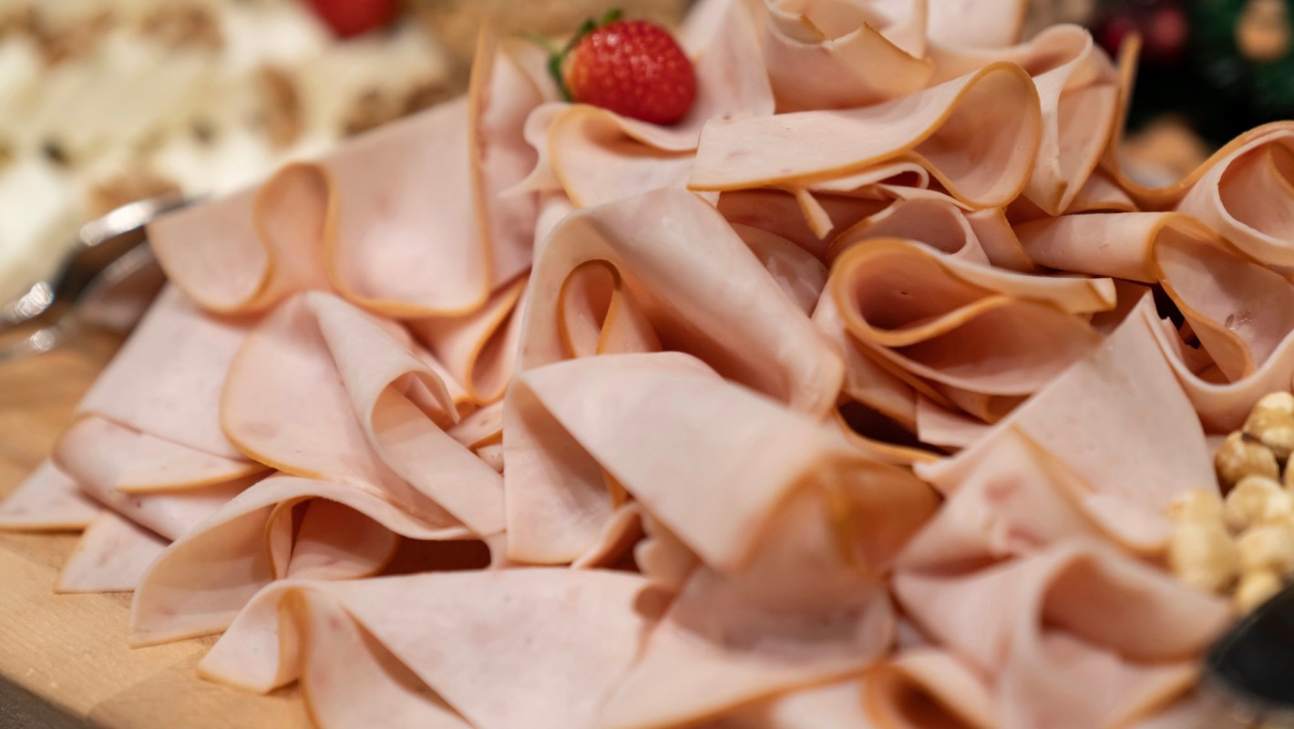 A close-up of neatly arranged slices of deli turkey with a strawberry on top.