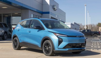 A blue Chevrolet Bolt electric vehicle outside a dealership.