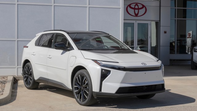 A white Toyota bZ SUV parked outside a dealership with a modern design and distinctive front features.