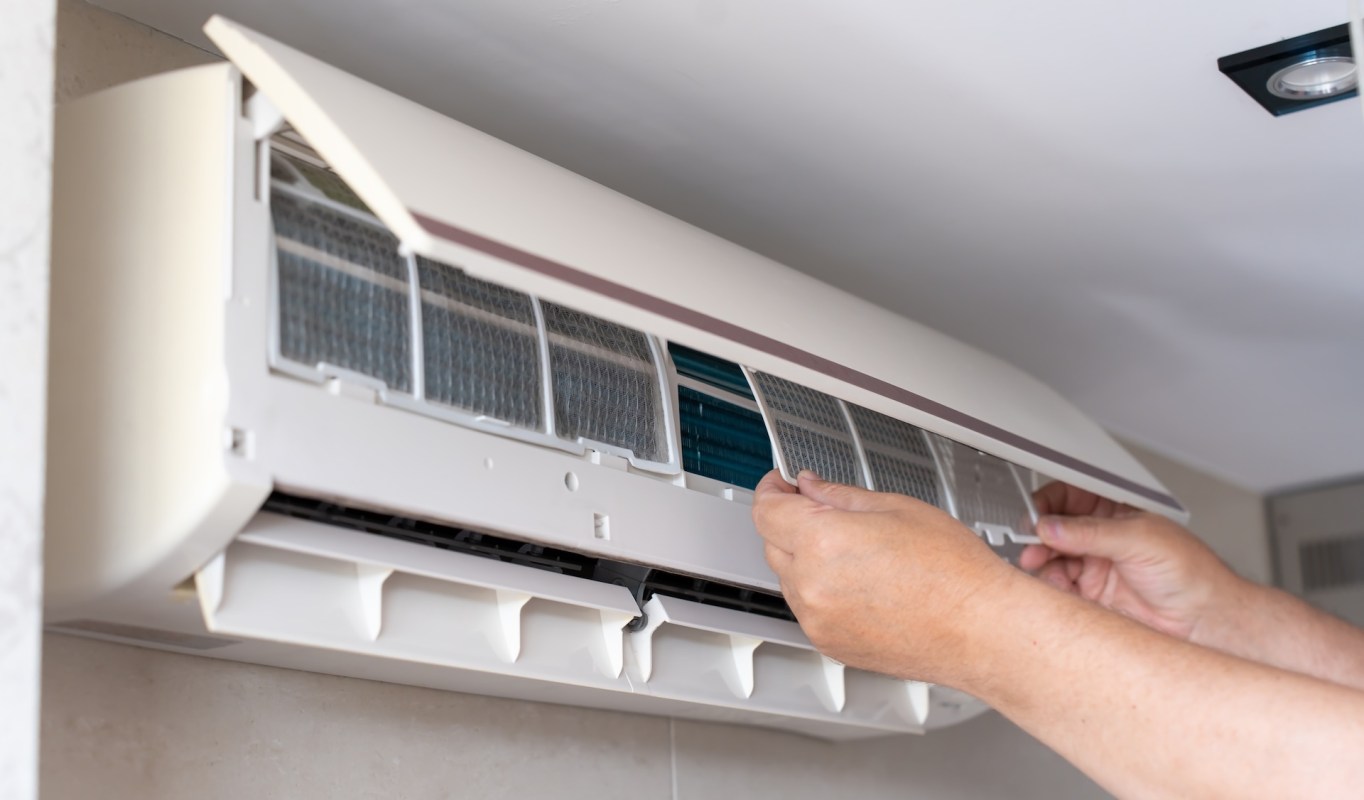 A person adjusting a filter on a mini-split HVAC unit.