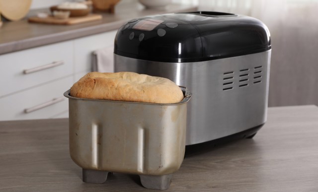 A loaf of bread next to a bread maker.