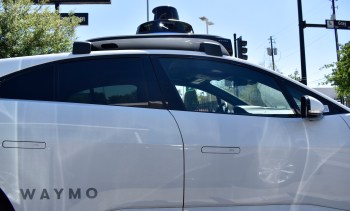 A Waymo self-driving car parked at an intersection, showcasing its automated features and sensors.