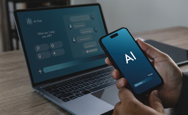 A person holds a smartphone displaying an AI chat interface next to a laptop showing a similar chat application.