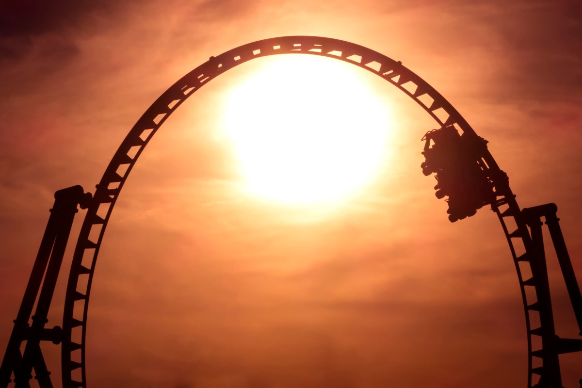 A roller coaster silhouetted against a bright sunset sky.