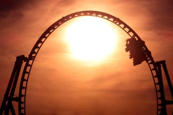 A roller coaster silhouetted against a bright sunset sky.
