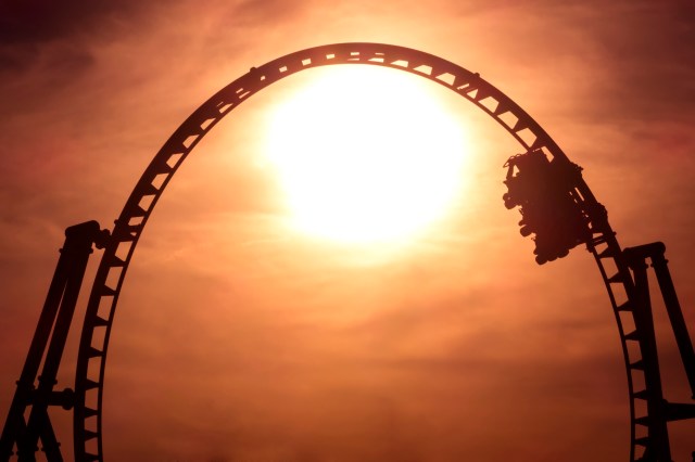 A roller coaster silhouetted against a bright sunset sky.