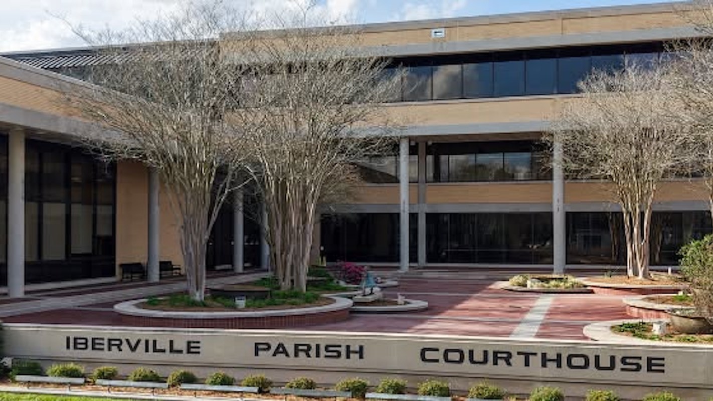 A modern courthouse building with landscaped grounds, featuring the name "Iberville Parish Courthouse" prominently displayed.