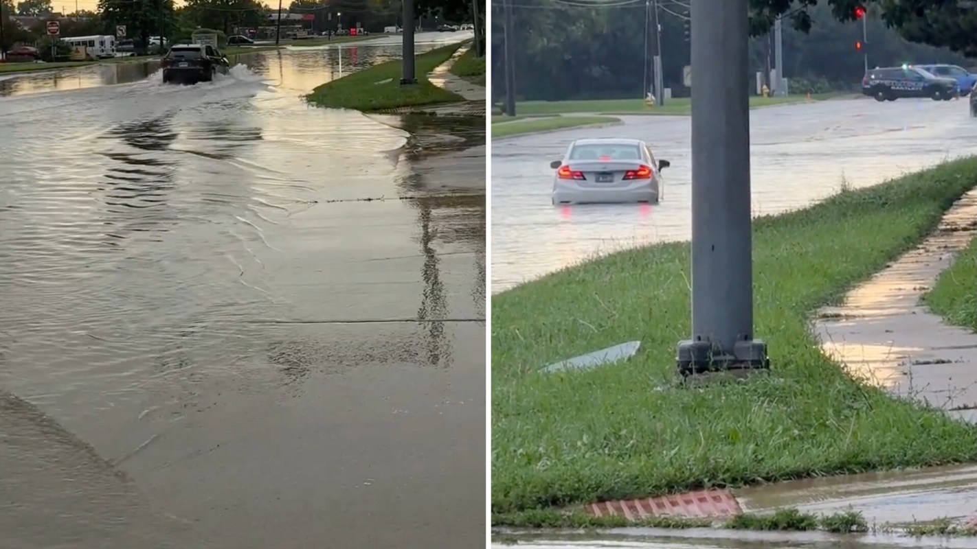 A flooded intersection with cars struggling to navigate through standing water.