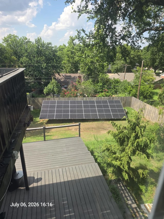 A solar panel array on the ground in a backyard.
