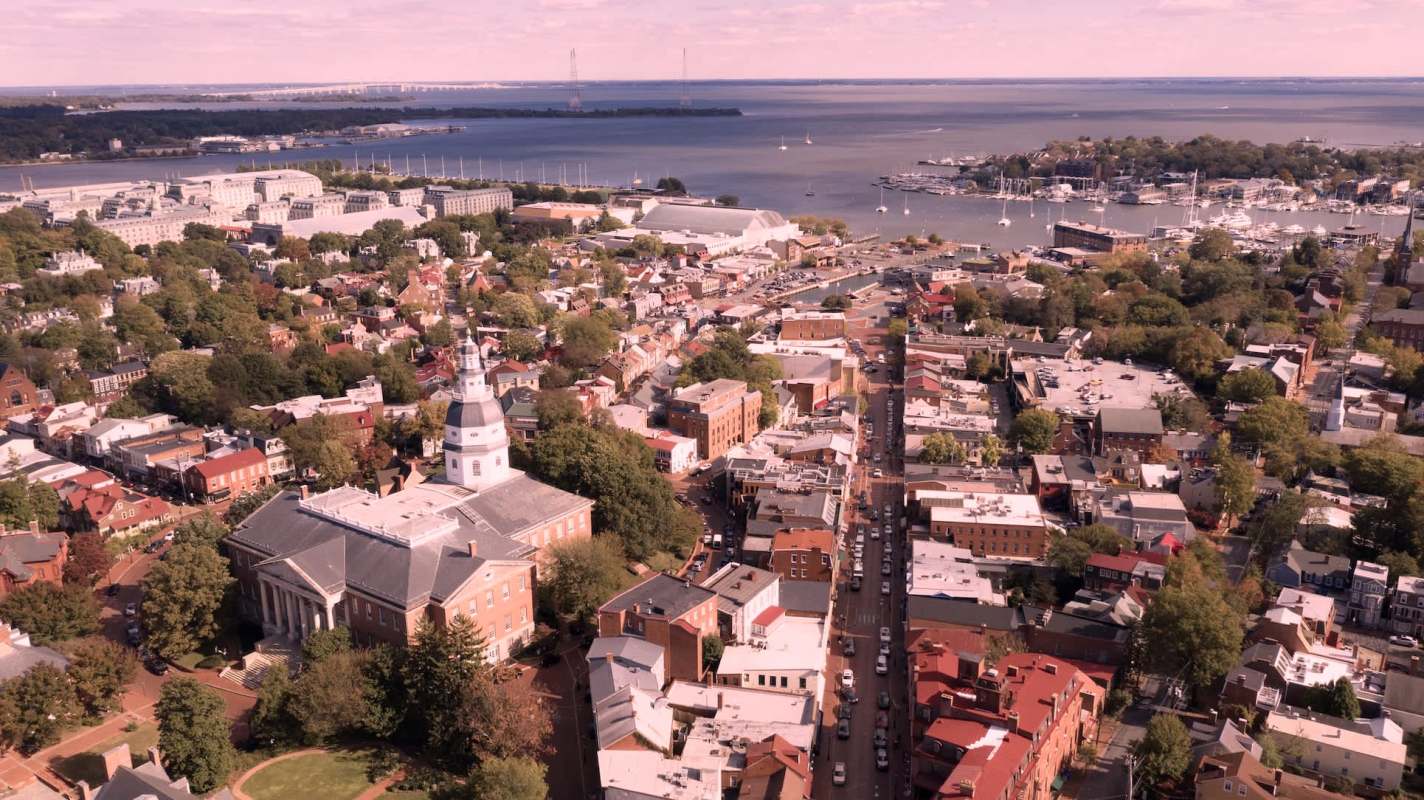 Aerial view of a waterfront city with historic buildings and boats along the shoreline.