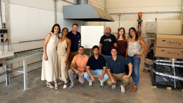 A group of eight people from Ionly stands in a warehouse with equipment and boxes.