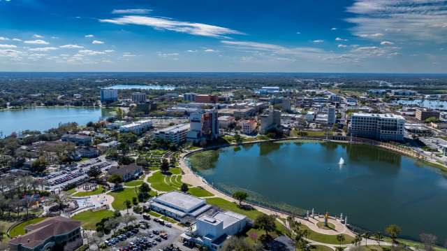 Aerial view of a lake surrounded by urban development and parks under a blue sky.