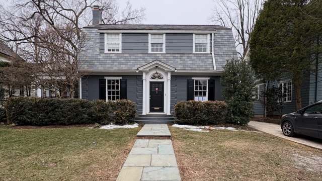 A two-story house with turf lining a stone walkway.
