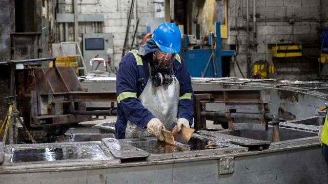 A worker in protective gear operates equipment in a manufacturing facility.