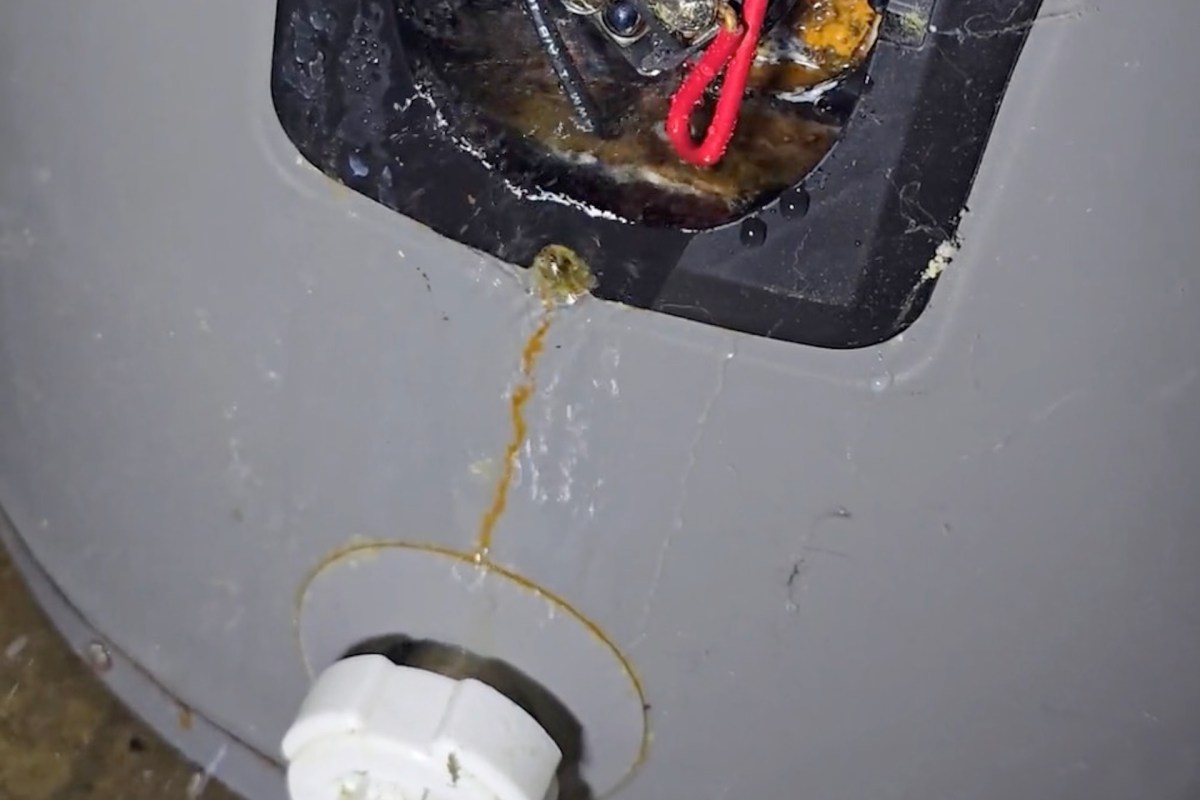 A close-up of a water heater showing rust and leaking near the electrical components.