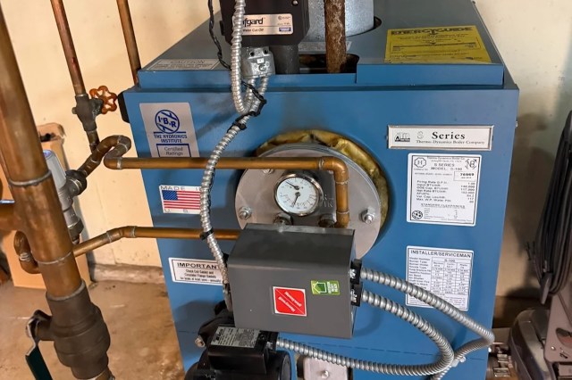A blue boiler with pipes, gauges, and safety labels in an industrial setting.