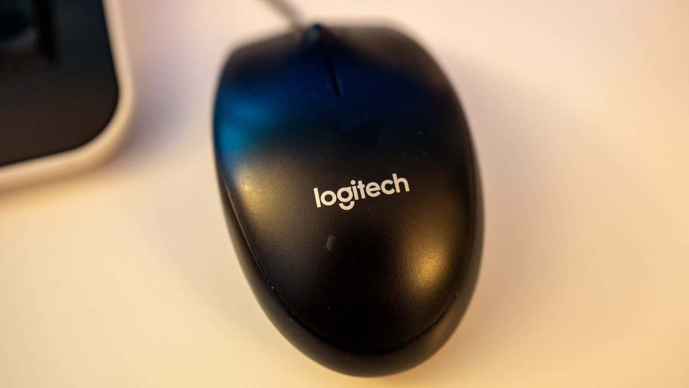 A black Logitech computer mouse on a light-colored surface.