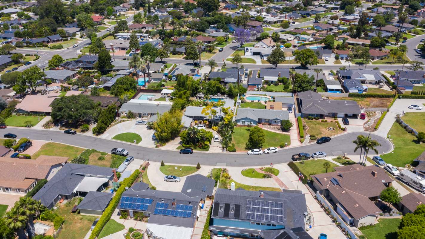 An aerial view of a suburban neighborhood with houses, gardens, and a circle drive.