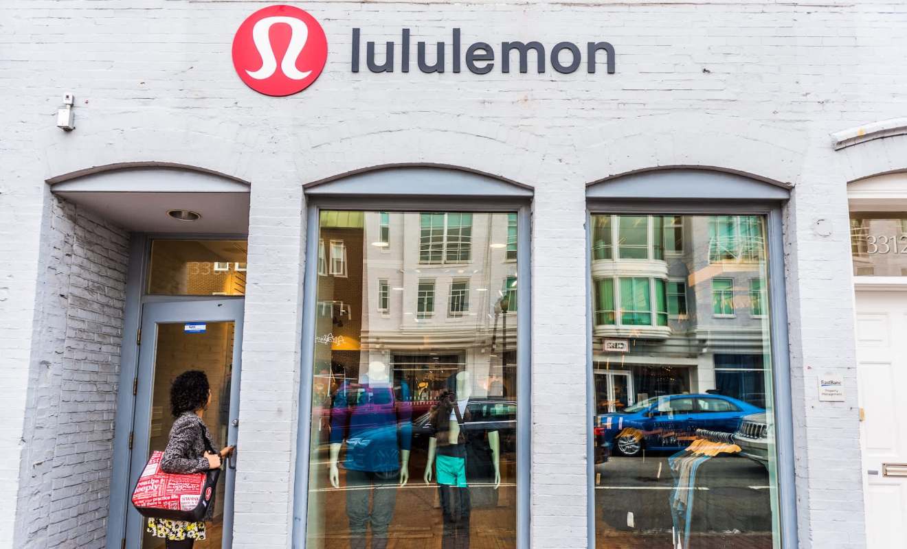 A storefront of a Lululemon store featuring mannequins and reflections of the street outside.