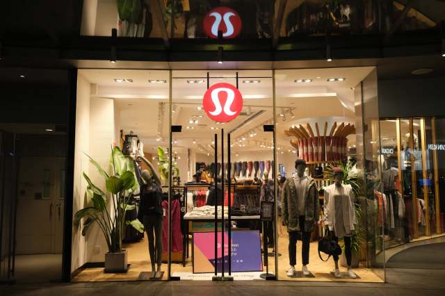 A storefront display of a clothing store featuring mannequins and a large logo above the entrance.