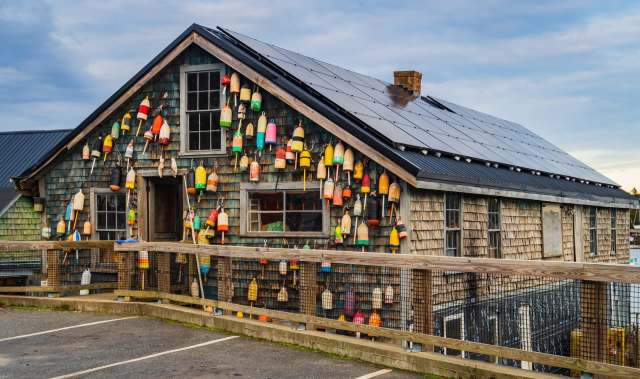 A building with rooftop solar panels and decorated with fishing buoys.
