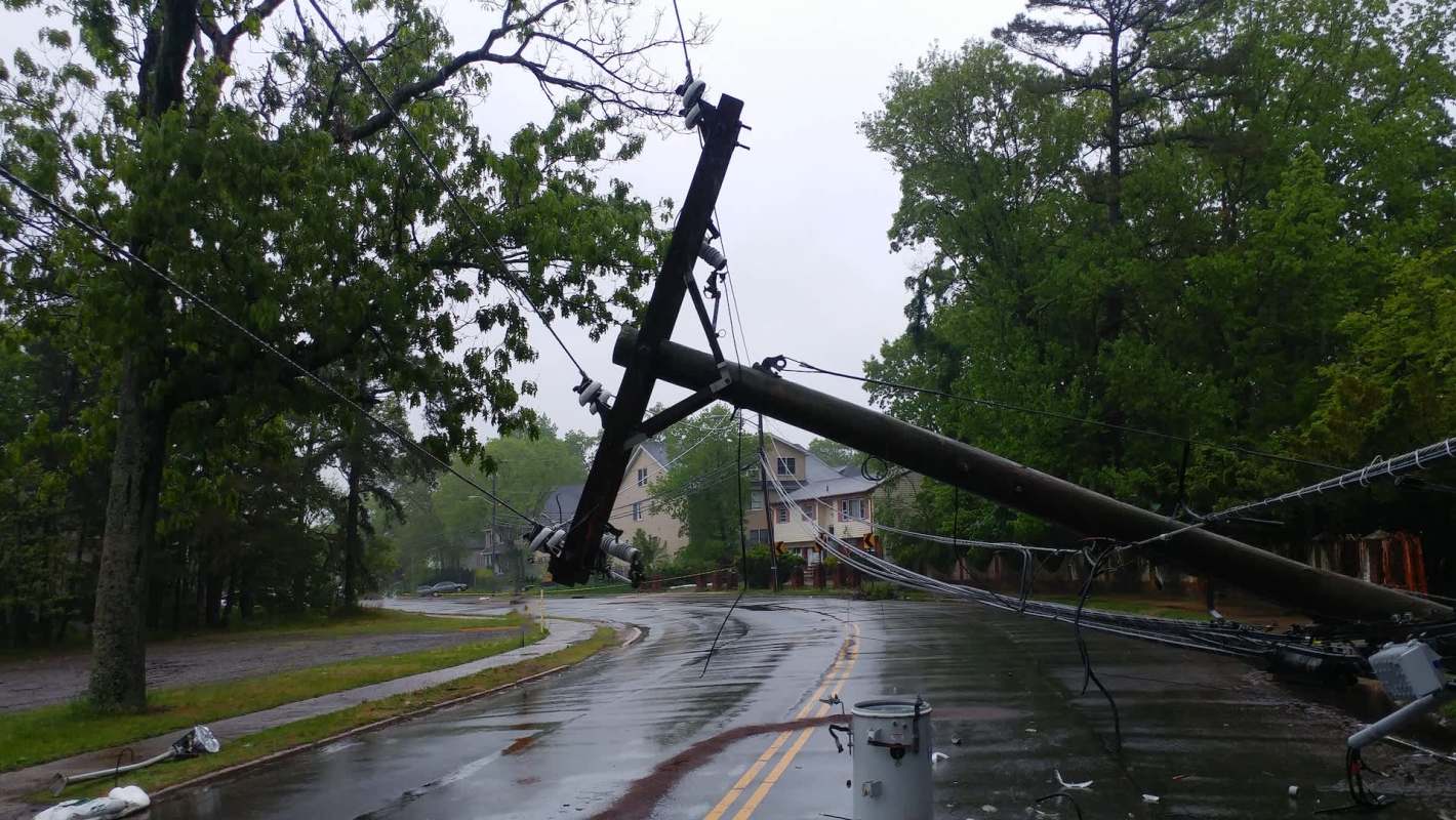 A fallen utility pole on a wet residential road.