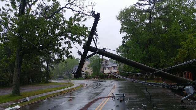 A fallen utility pole on a wet residential road.