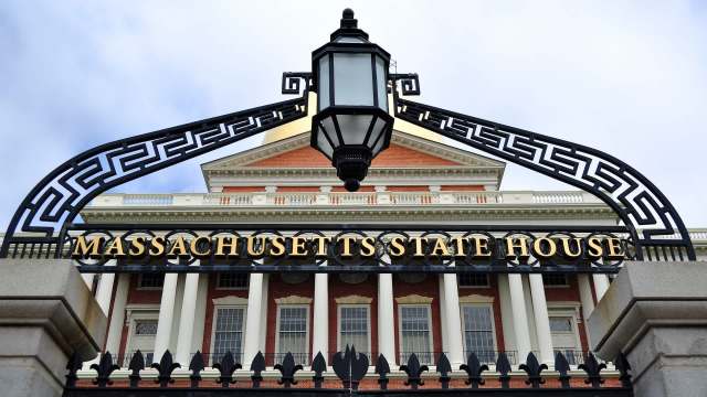 The ornate entrance gate of the Massachusetts State House featuring golden lettering and a decorative lantern.