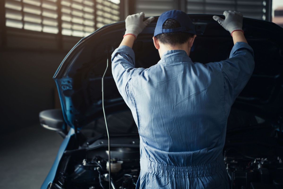 A mechanic looking under the hood of a car.