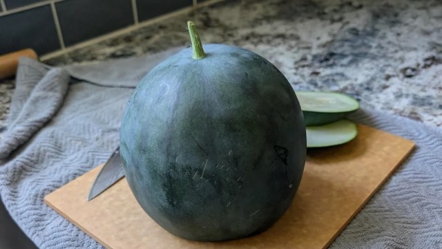 A Sugar Baby watermelon on a cutting board.