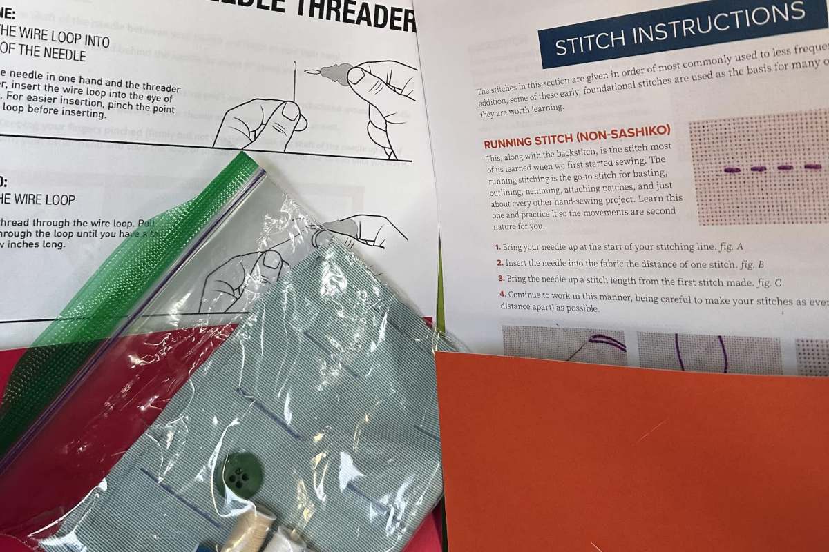 A collection of sewing materials, including instructions, fabric, buttons, and thread, arranged on a table.