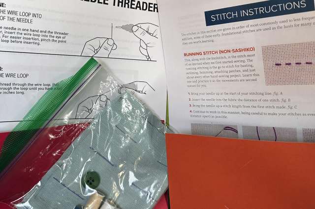 A collection of sewing materials, including instructions, fabric, buttons, and thread, arranged on a table.