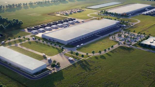 An aerial view of a large industrial complex surrounded by greenery and parking areas.