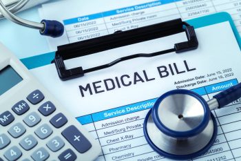 A medical bill document with a calculator and stethoscope on a table.
