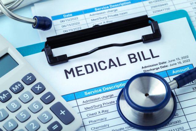 A medical bill document with a calculator and stethoscope on a table.