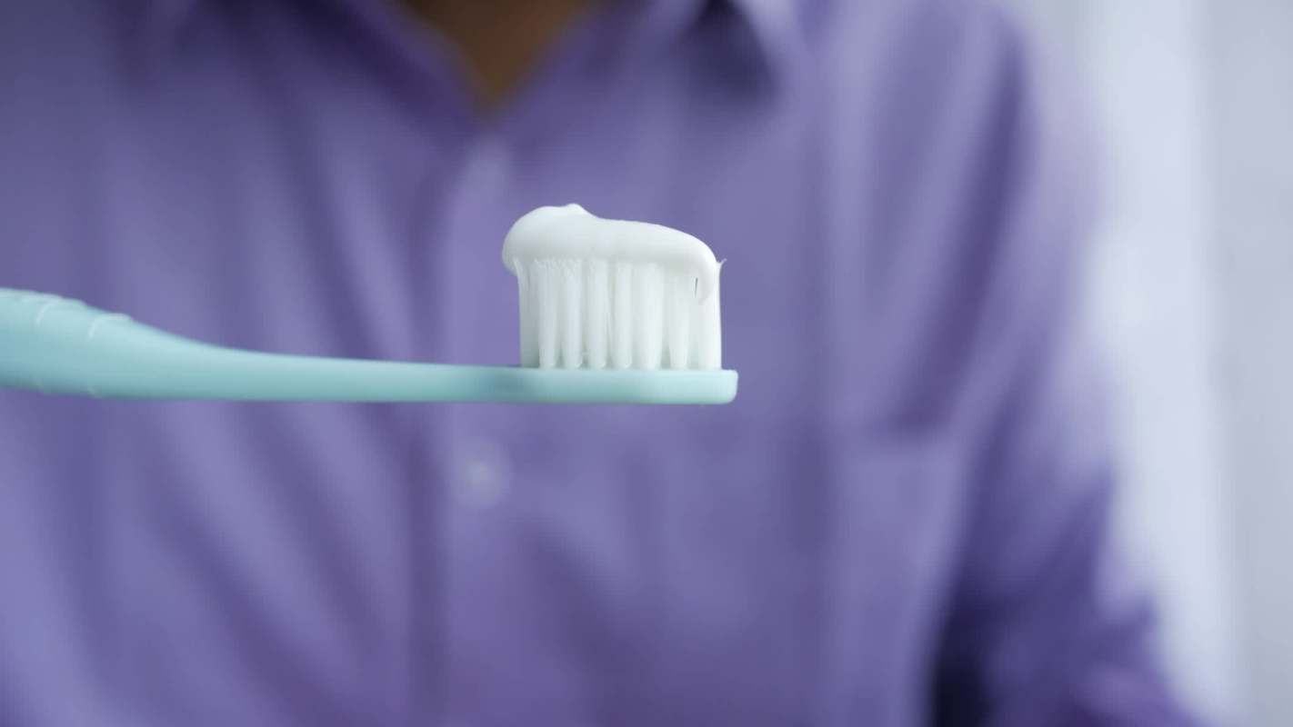 A person holding a toothbrush with toothpaste.