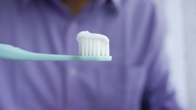 A person holding a toothbrush with toothpaste.