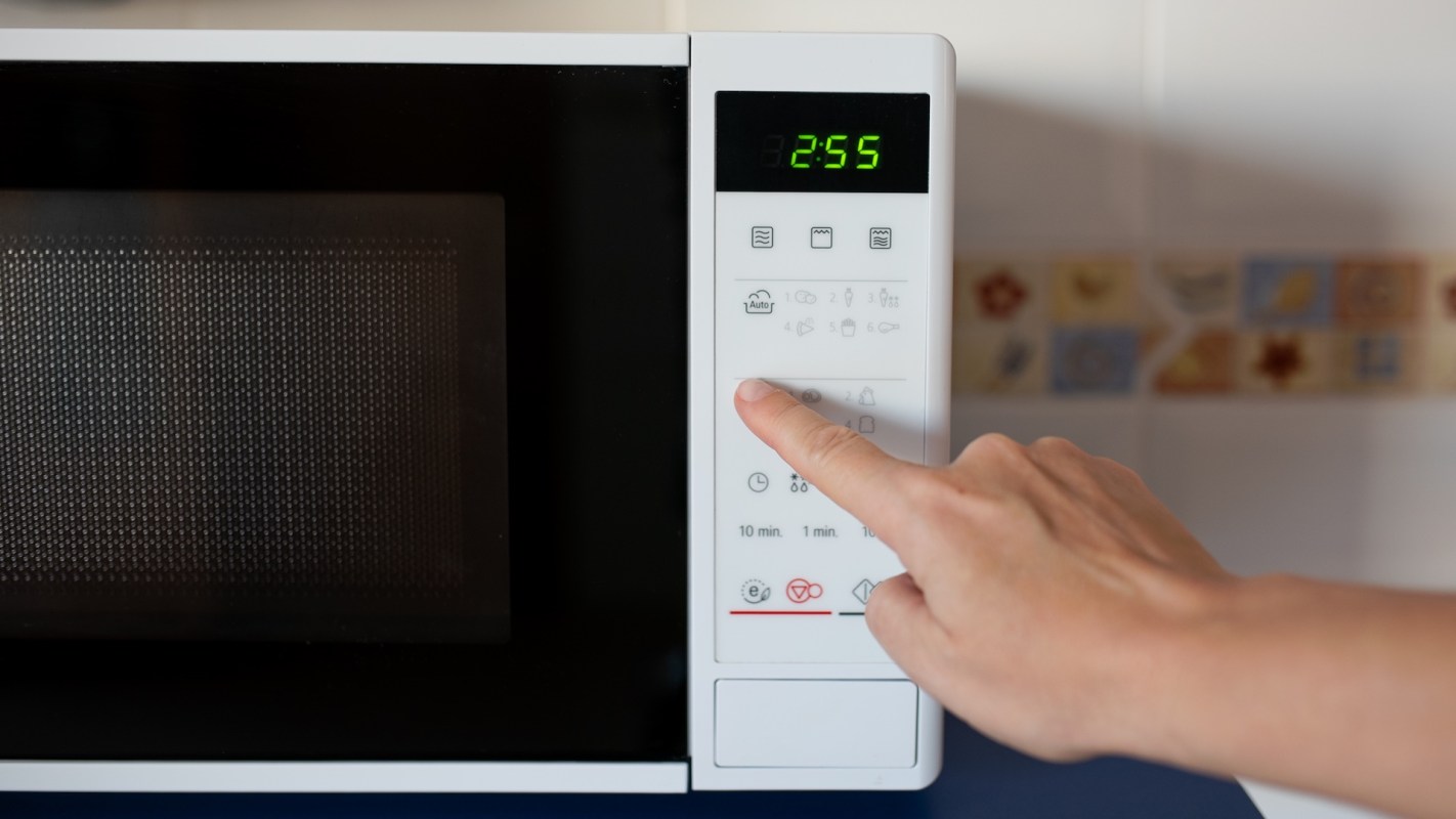 A person programming a microwave.