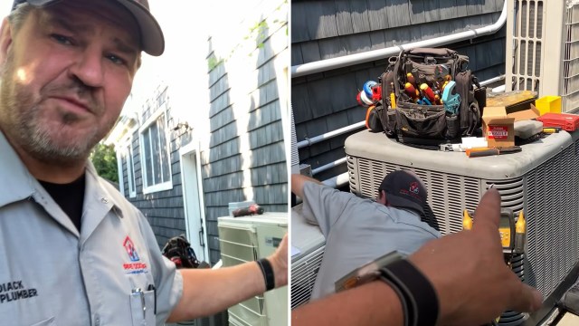 A technician gestures toward an air conditioning unit while another technician works on it outside a house.