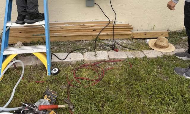 The outside of a house with a ladder and cables visible against the wall.