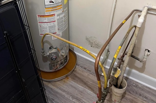A water heater next to a wall with mold.