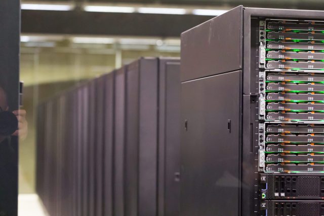 A row of sleek black server racks with illuminated hard drive bays in a modern data center.