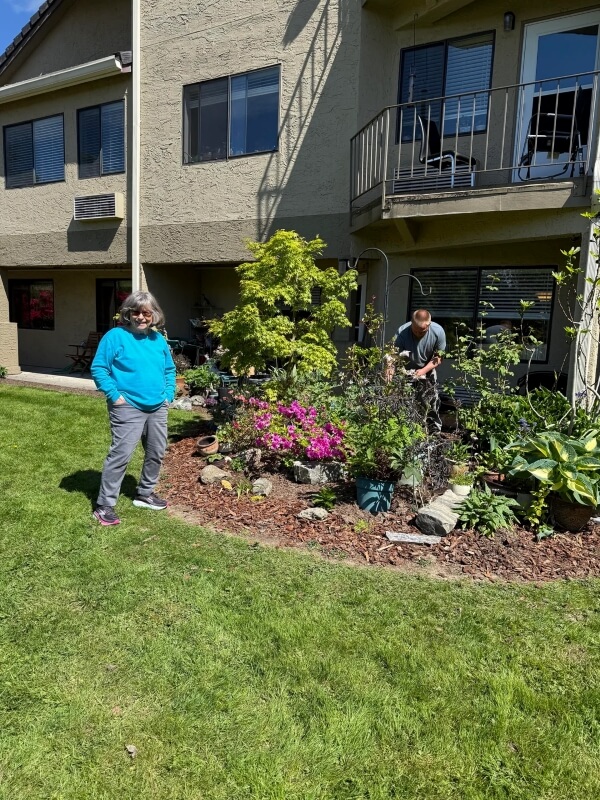 A woman standing in front of a garden.