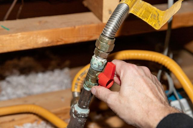 A person turning a natural gas safety valve.