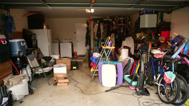 A cluttered garage filled with boxes, bikes, children's toys, and storage bins.